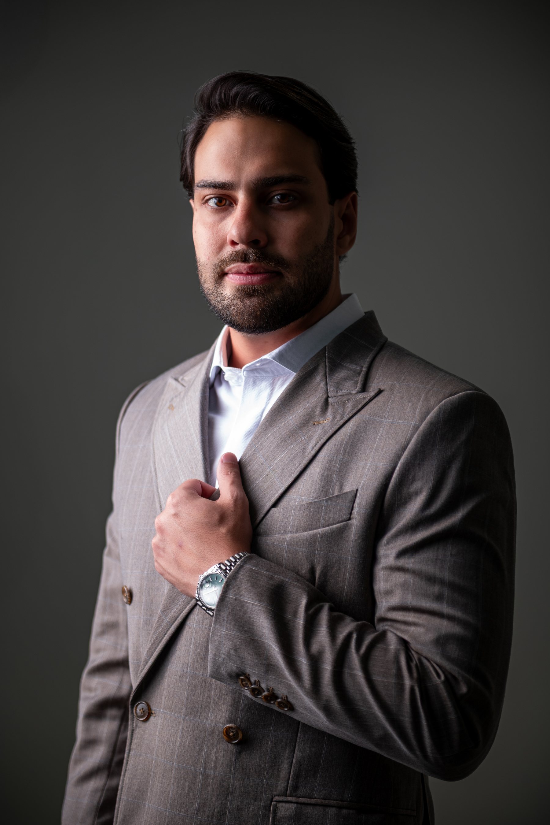 Dr. Lucas Martins, de terno cinza, em retrato profissional com fundo escuro