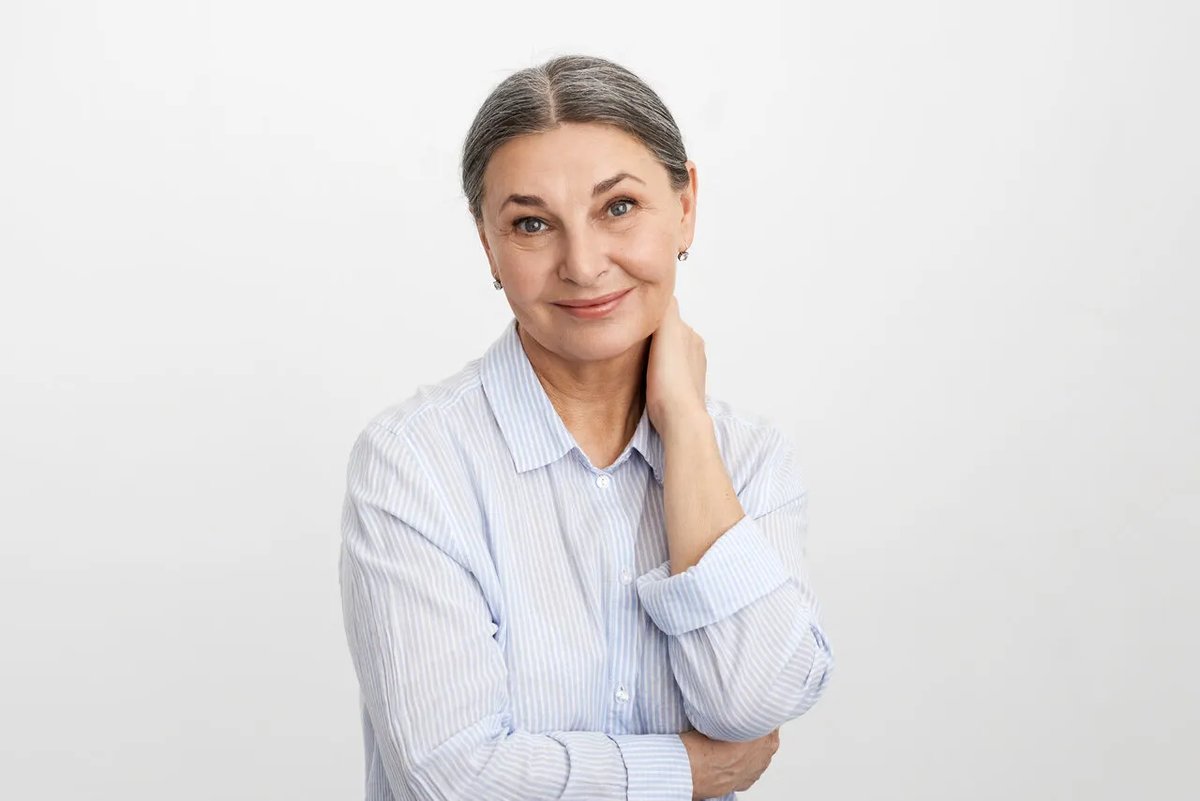 Mulher madura de camisa clara sorrindo, representando o cuidado na menopausa